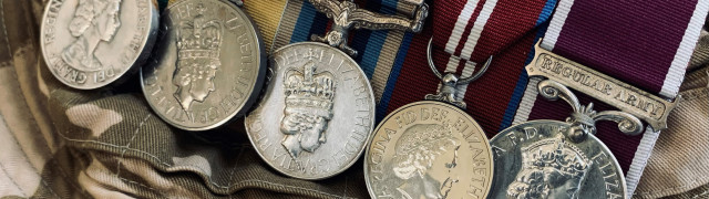 row of 5 military medals on top of a camouflage hat