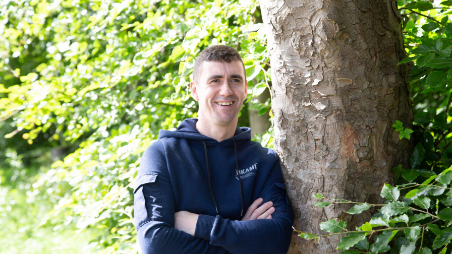 Veteran Steven leaning against tree looking relaxed and smiling