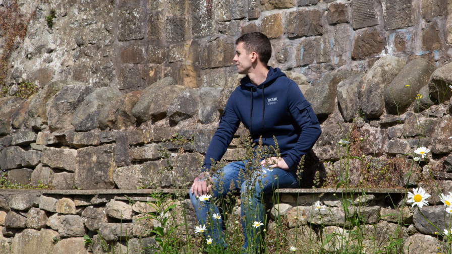 Veteran Steven sitting on a stone wall looking away
